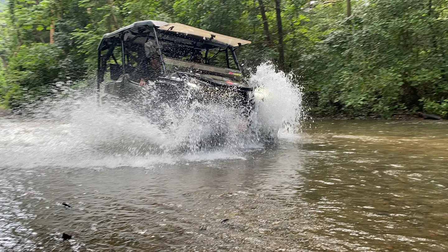 UTV side by side crossing a river at full speed